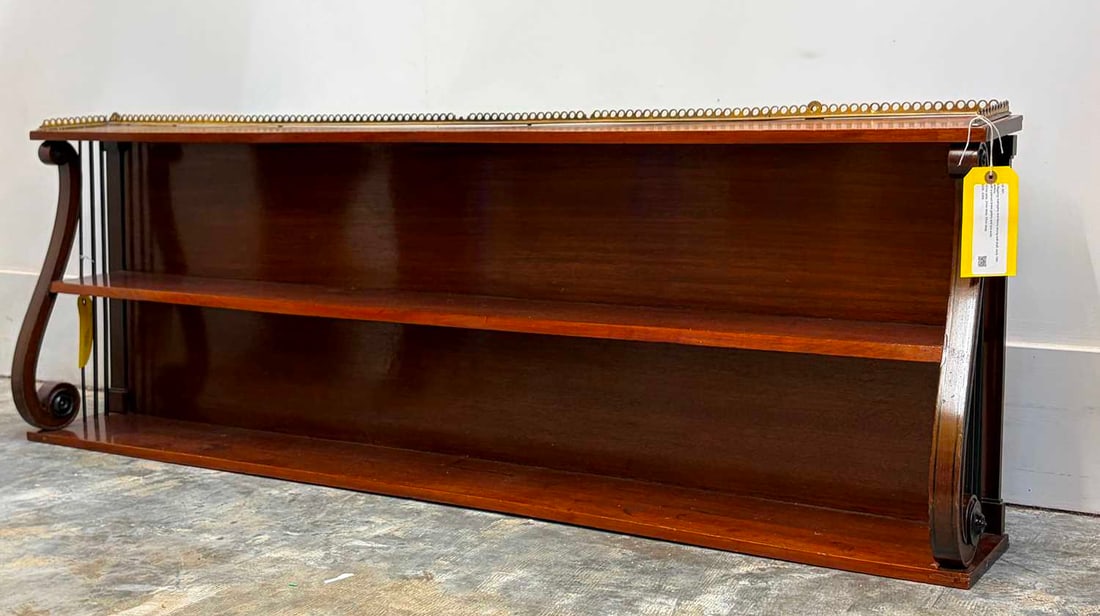 A Regency mahogany and ebony strung wall shelf, early 19th century,: A Regency mahogany and ebony strung wall shelf, early 19th century, with a pierced brass gallery and lyre ends 151cm wide, 21cm deep, 52cm deepCondition Report: Possibly the superstructure of a chiff