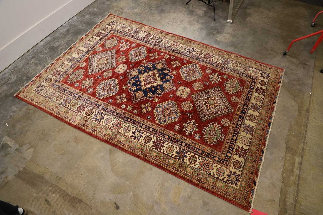 A Kazak wool rug, late 20th century,: A Kazak wool rug, late 20th century, the red ground with a central royal blue medallion and a geometric border 249 x 173cm Condition Report: Some wear throughout. Tassels have been cut down.