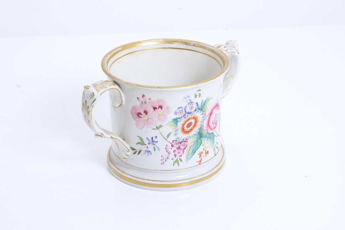 A Staffordshire two-handled loving cup, 19th century,: A Staffordshire two-handled loving cup, 19th century, of large proportions, with floral spray to each side painted in polychrome, the moulded handles, and borders with gilt decoration 20.5cm high 