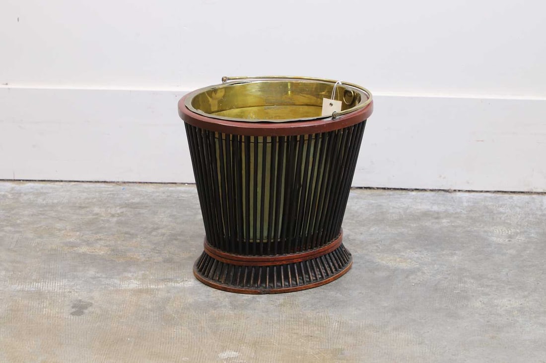 A wood and brass bucket, 20th century,: A wood and brass bucket, 20th century, the brass liner with carrying handle encased in a wooden frame with turned struts 37cm wide, 33cm high Condition Report: Loss to some of the turned