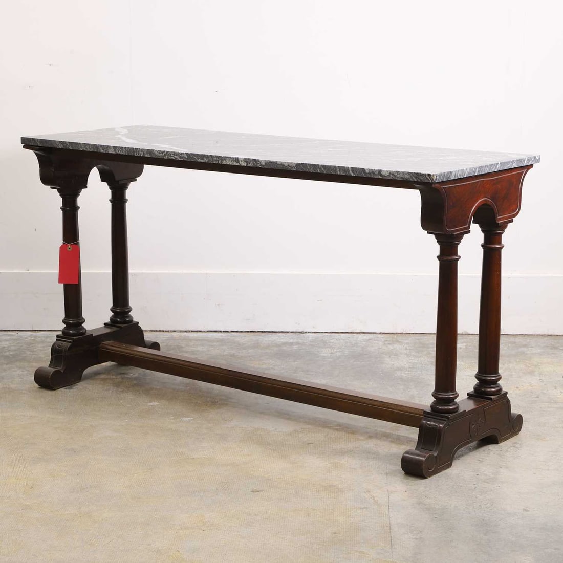 A Spanish mahogany library table, late 19th century,: A Spanish mahogany library table, late 19th century, the rectangular black marble top over twin columned supports, the scrolling feet joined by stretcher, each side with engraving and single burst