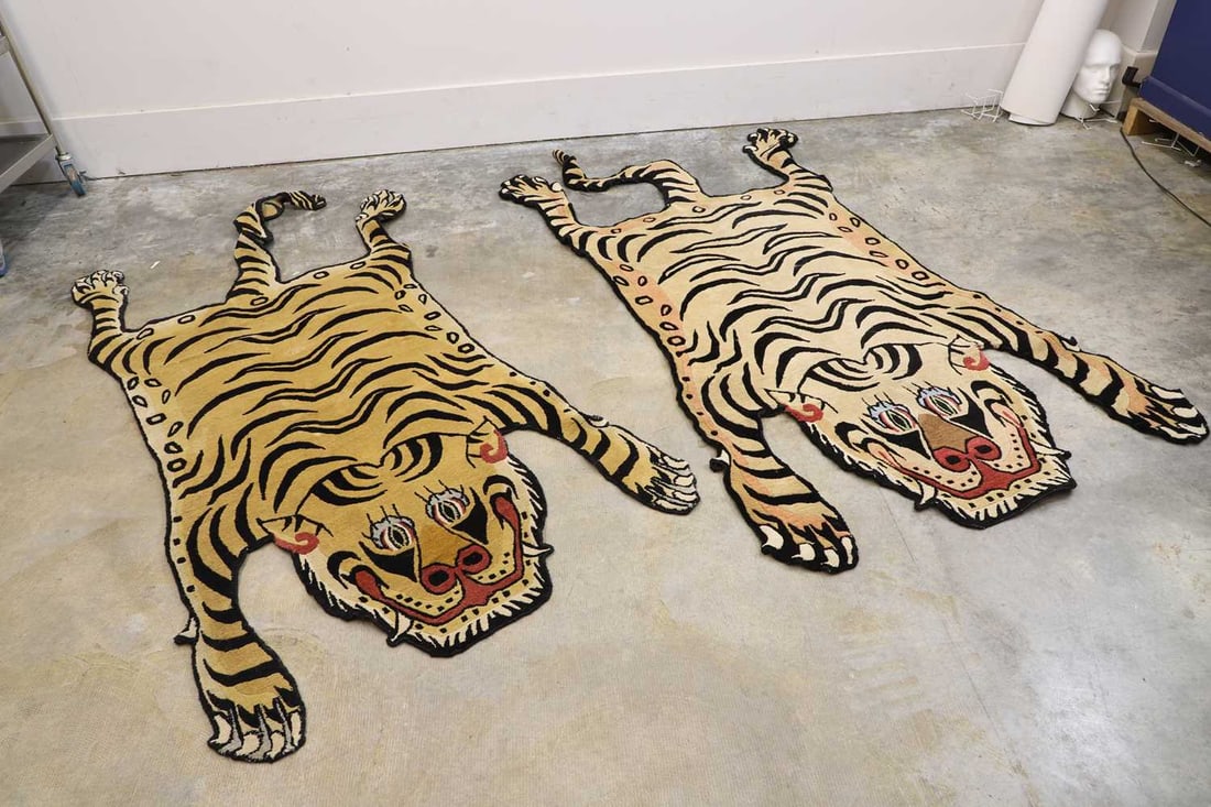 A pair of tiger rugs, 21st century,: A pair of tiger rugs, 21st century, in the shape of tigers lying flat 97cm wide, 183cm long 2 Condition Report: Tears to the edges and some wear on the sides.