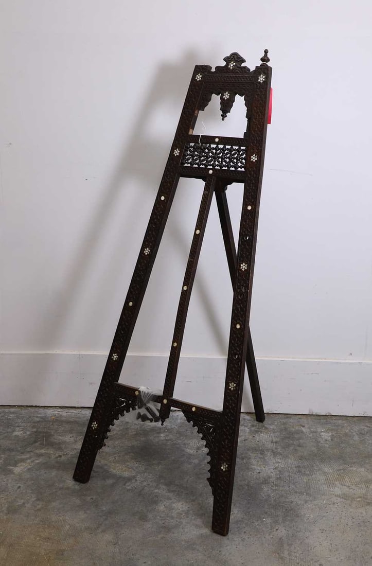 A carved and inlaid Moroccan easel, 20th century,: A carved and inlaid Moroccan easel, 20th century, inlaid with mother of pearl, with two peg supports, mounted with finials 135cm high 4 Condition Report: One finial loose. Pegs and finial in