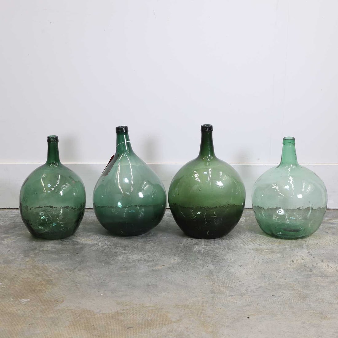 A group of four glass olive jars, early 20th century,: A group of four glass olive jars, early 20th century, of globular form with slender necks, of various tones 33cm wide 50cm high 4 Provenance: The Select Contents of a Provincial French Estate.