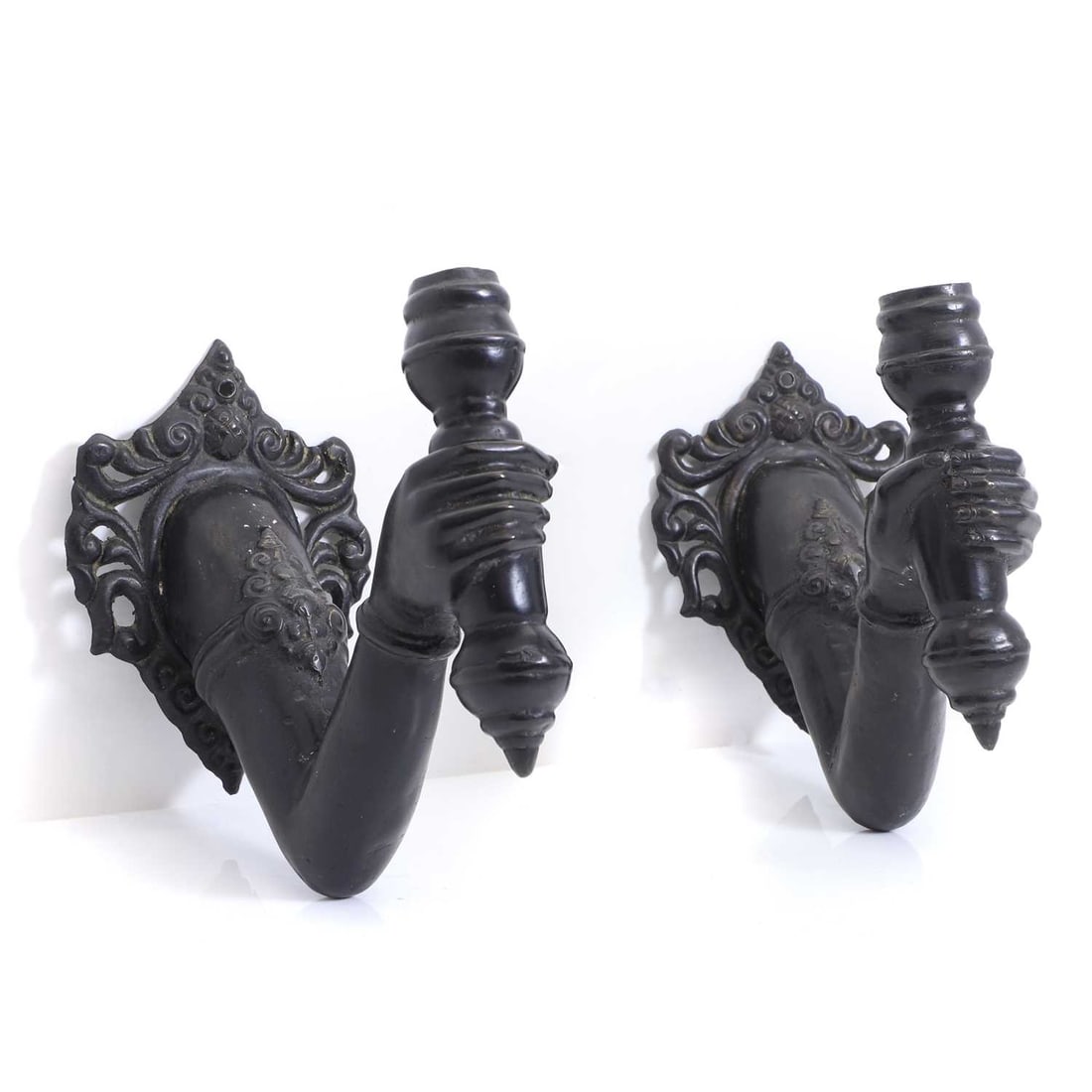A pair of black wall lights, early 20th century,: A pair of black wall lights, early 20th century, modelled as Indian hands and arms holding torches with stylised brackets, 25 wide, 12 deep, 28cm high 2 Provenance: The Select Contents of a