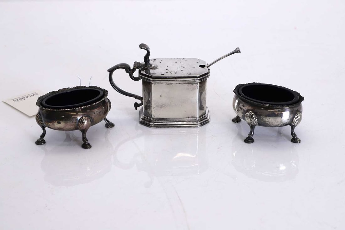 A group of silver cruets,: A group of silver cruets, comprising a mustard pot, by S W Smith & Co, London 1911, of octagonal form with moulded base and conforming hinged cover, the interior with blue glass liner together
