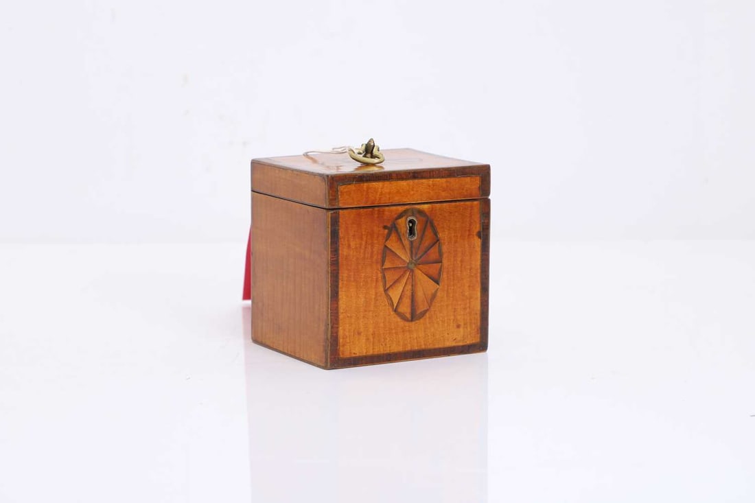 A small square sycamore tea caddy, 20th century,: A small square sycamore tea caddy, 20th century, with paterae inlay to the lid and front, with a brass handle to the lid enclosing a single compartment 10.8cm wide, 9.4cm deep, 12cm high