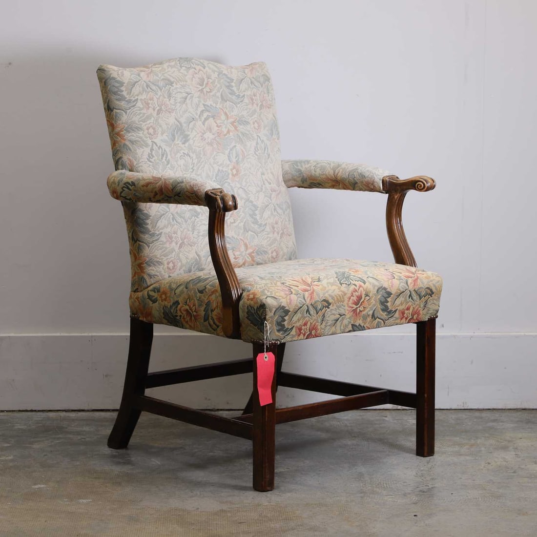 A mahogany framed armchair, 18th century,: A mahogany framed armchair, 18th century, the arched back, arms and seat upholstered in foliate tapestry type fabric, the arms terminating in knurl scrolls, raised on square moulded supports united