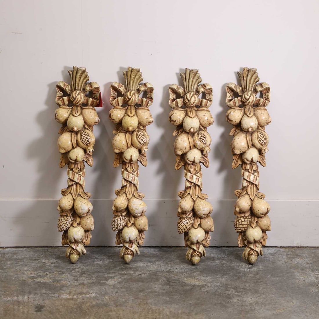 A set of four carved and painted wooden wall appliques, late 19t h/ early 20th century,: A set of four carved and painted wooden wall appliques, late 19t h/ early 20th century, in the form of swags of fruit and foliage 20cm wide, 7cm deep, 80cm high 4 Provenance: The Select Contents