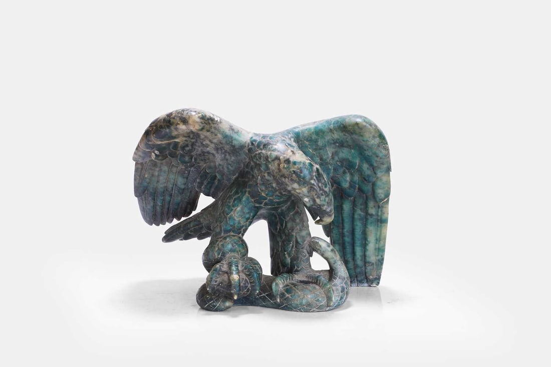 A hardstone model of an eagle, late 19th/early 20th century,: A hardstone model of an eagle, late 19th/early 20th century, modelled in flight catching a snake, the mottled green stone with white inclusions 31cm wide, 18cm deep, 23cm high