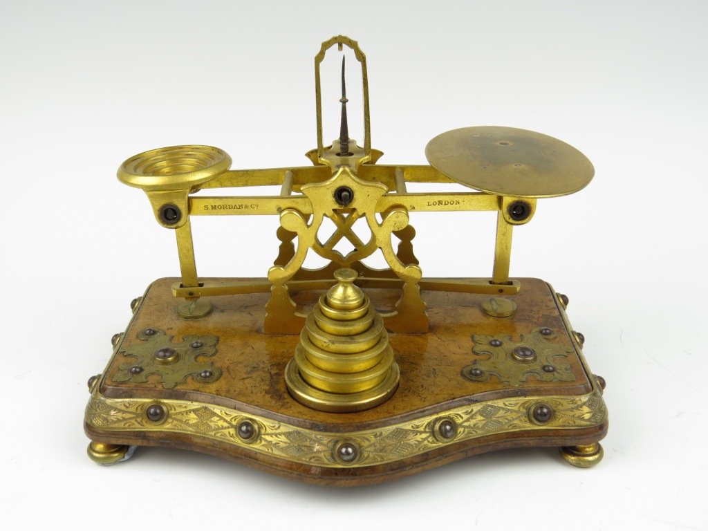 Sampson Mordan & Co., a set of gilt metal and walnut d: Sampson Mordan & Co., a set of gilt metal and walnut decorative postal scales, c.1871-1885, stamped to the beam 'S. Mordan & Co, London', set on a burr walnut base, having applied engraved gilt metal 