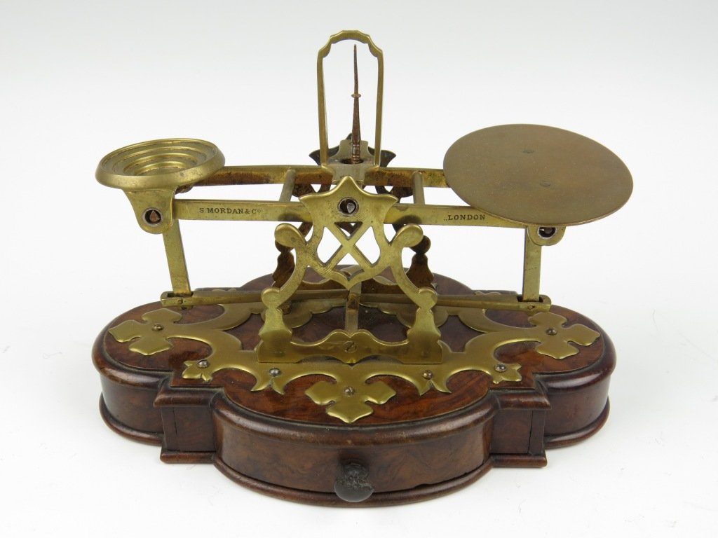 Sampson Mordan & Co., a rare brass postal scale, c.188: Sampson Mordan & Co., a rare brass postal scale, c.1880, the beam stamped 'S. Mordan & Co, London', having a circular stepped pan and oval plate, upon a walnut quatreform base with plush lined drawer,