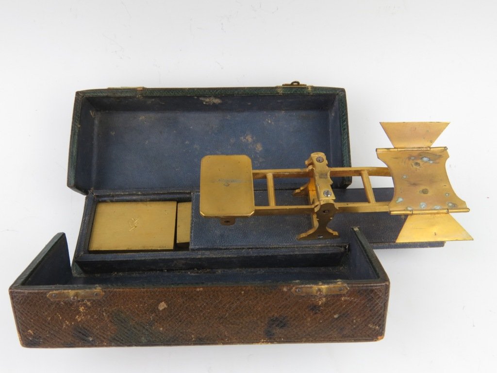 Sampson Mordan & Co., a matt gilt brass travelling pos: Sampson Mordan & Co., a matt gilt brass travelling postal scale, 19th century, with folding letter plate upon a shaped solid 'A' frame and blue leather base, all within a fitted leather side hinged bo