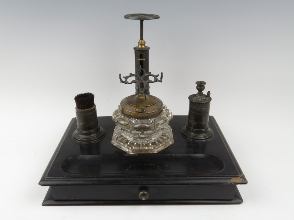 A lacquered desk compendium, c.1850, with Wharton type: A lacquered desk compendium, c.1850, with Wharton type 'candlestick' letter scale, with taper stick, nib wipe and inkwell upon a plain lacquered base with single drawer, capacity 4oz, 26.5cm wide, 22.