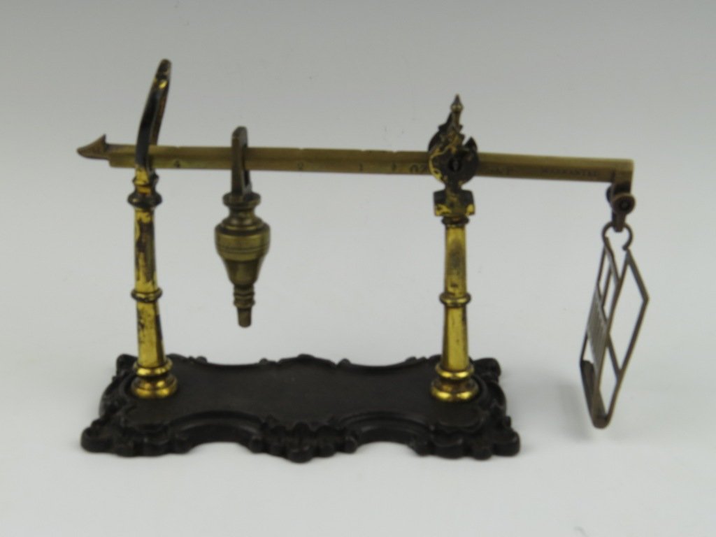 Simcox & Pemberton, a brass steelyard postal scale, c.: Simcox & Pemberton, a brass steelyard postal scale, c.1840, the beam stamped 'S & P Warranted' with a turned poise, on turned and gilded supports upon a rococo style cast base, capacity 4oz, 20cm wide