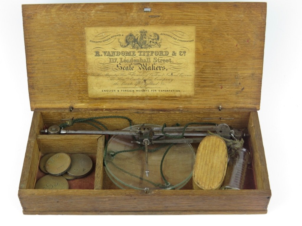 R. Vandome Titford & Co., steel apothecary scales, c.1: R. Vandome Titford & Co., steel apothecary scales, c.1850, the beam with box end terminals supporting glass circular pans, within an oak box, the lid interior with applied label for 'R. Vandome Titfor