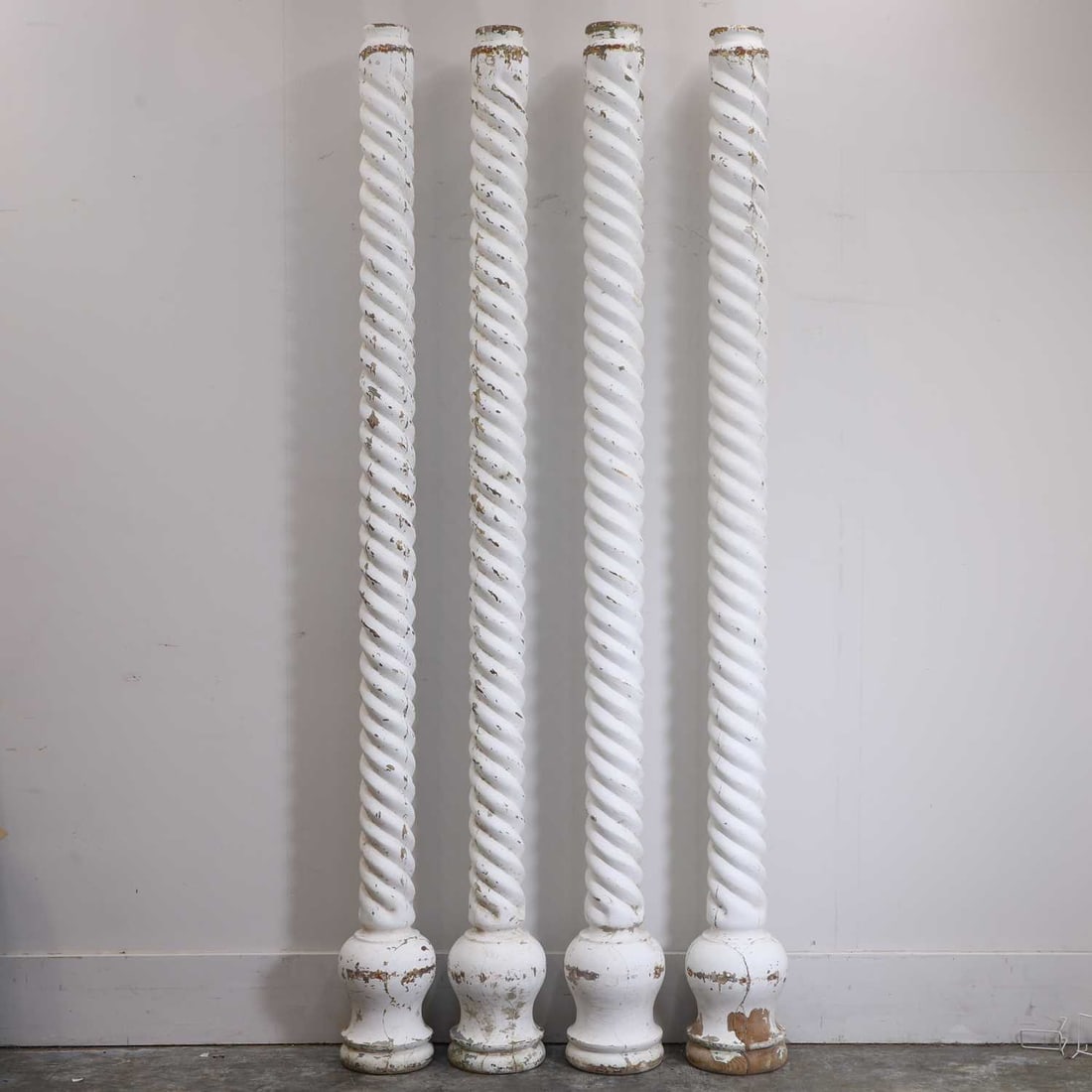 A set of four wooden twisted columns, early 20th century,: A set of four wooden twisted columns, early 20th century, , painted white, flaking to reveal gilt paint underneath, possibly fairground 28cm wide, 230cm high 4 Provenance: The Select Contents of a