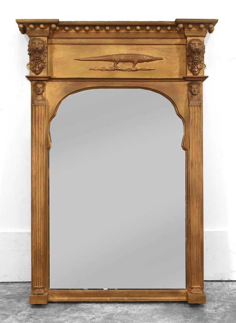A Regency giltwood pier mirror, 19th century,: A Regency giltwood pier mirror, 19th century, the arched plate flanked by fluted pilasters with mask surmonts, the frieze with crocodile mount 74x104cm