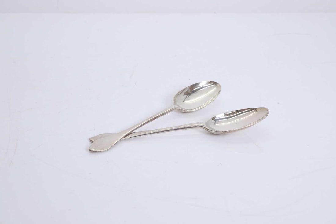 A pair of silver dog nose finial tablespoons,: A pair of silver dog nose finial tablespoons, maker mark RK, early 18th century, marks worn, with rail tail bowls, each engraved 'M/JC' 20.5cm long, 4.5ozt 2 Condition Report: Wear and marks rubbed.