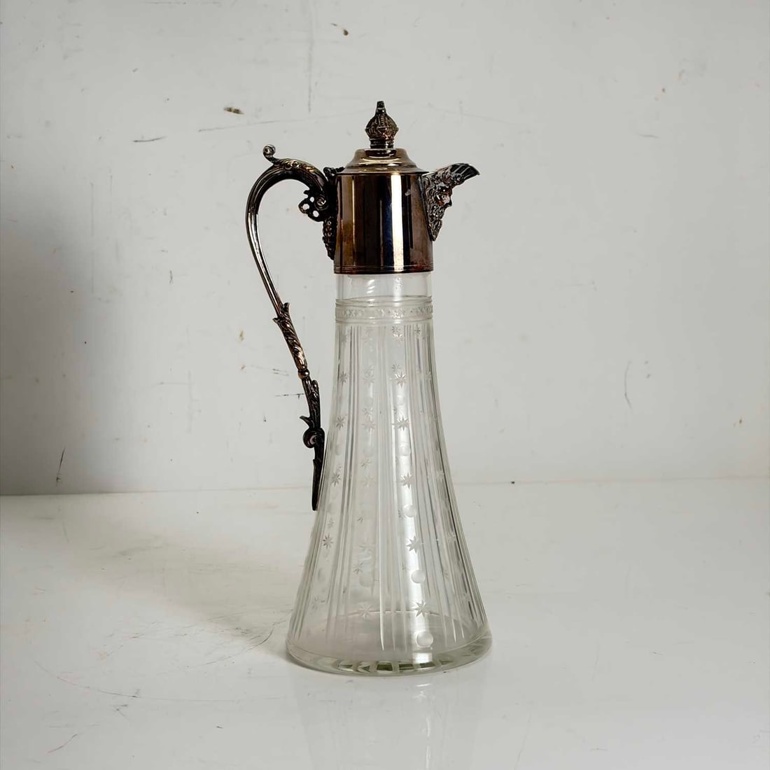 A silver-plated claret jug, 20th century,: A silver-plated claret jug, 20th century, with a cut glass tapering body, and mask shaped spout 28.5cm high Condition Report: Some rubbing to the plated mounts.