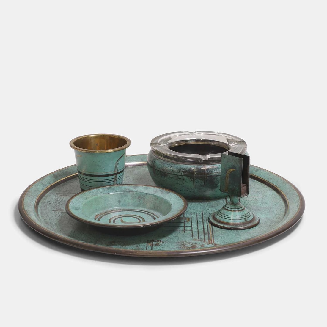A WMF 'Ikora' Art Deco patinated bronze smoking set, circa 1930s,: A WMF 'Ikora' Art Deco patinated bronze smoking set, circa 1930s, comprising a large ashtray with a glass insert, a small dish, a beaker, together with a tray, and a match holder, each with a mottled 