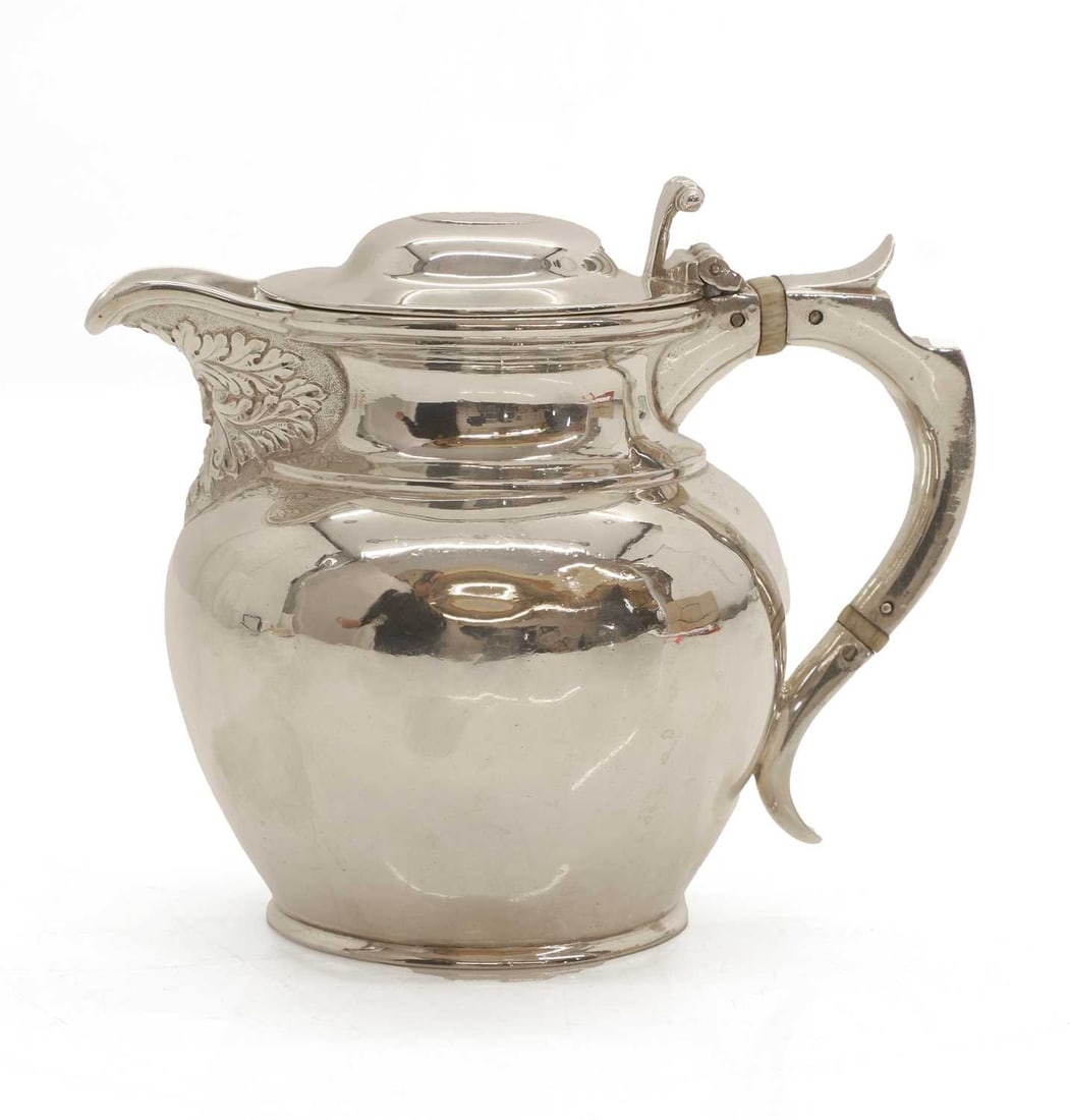 A silver lidded masked jug, circa.1900: A silver lidded masked jug, circa.1900 by George Edward & Sons (David & George Edward), Glasgow, 1903, the spout decorated with mask detail and coin inlaid to the lid, and ivory insulators