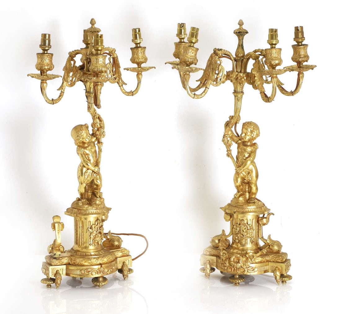 A pair of gilt brass Louis XVI style ormolu brass figural table candelabra, 19th century,: A pair of gilt brass Louis XVI style ormolu brass figural table candelabra, 19th century, each cast with a putto supporting scrolling foliate branches issuing four acanthus-cast candle arms, above a