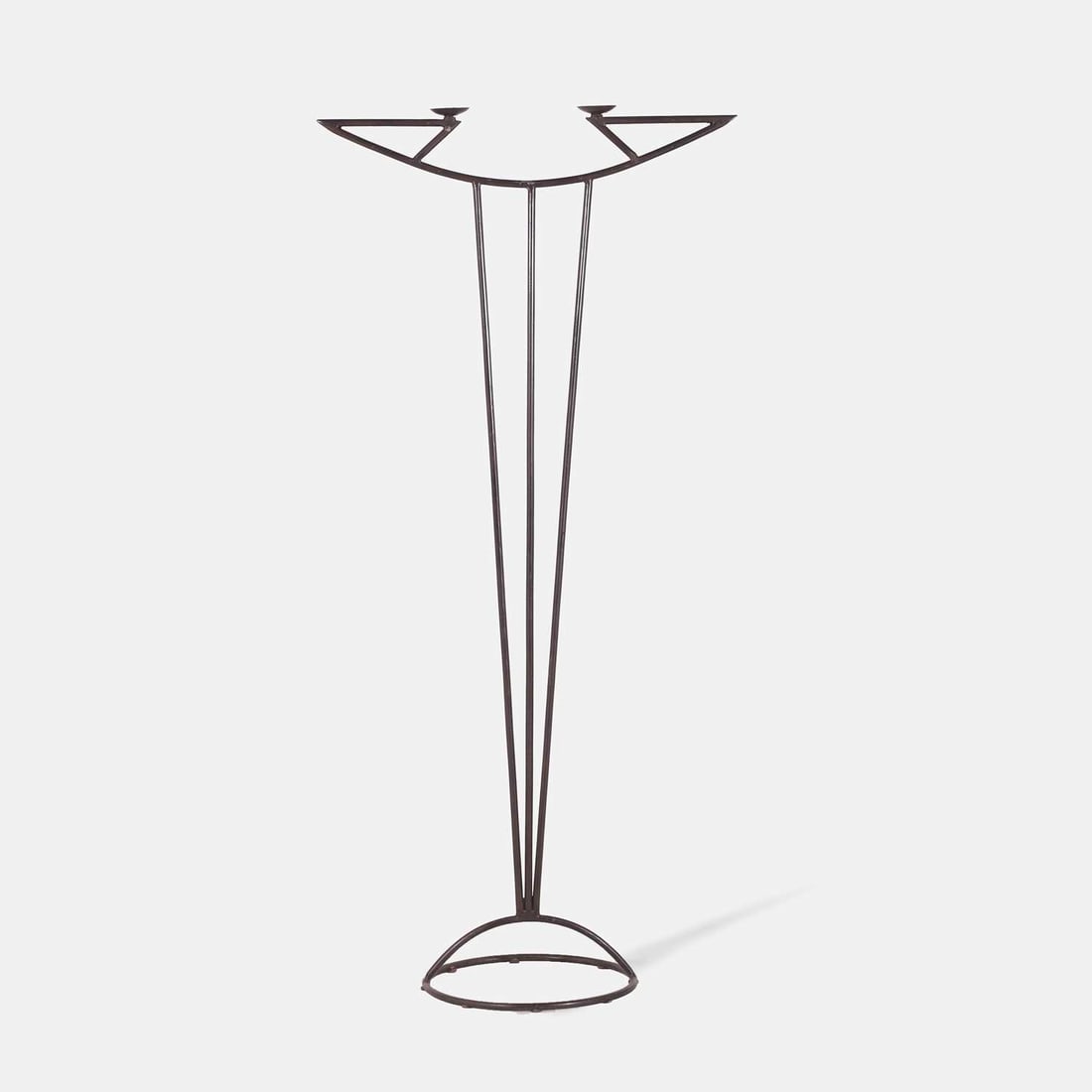 A Modernist wrought iron floor standing candlabrum, circa 1970s,: A Modernist wrought iron floor standing candlabrum, circa 1970s, the slender tapering supports rising to a shaped upper rail with two opposed candleholders, the base of arched outline, in painted