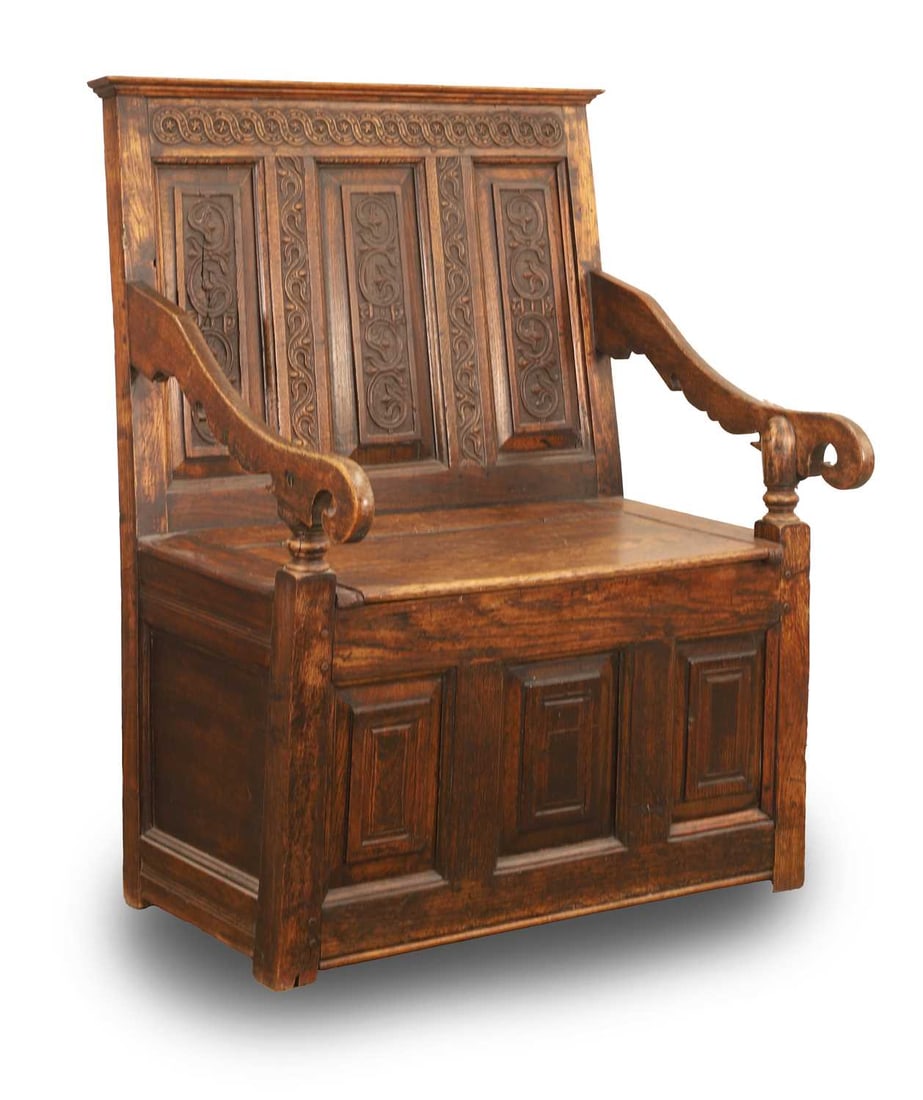 An oak monks bench,: An oak monks bench, with carved back panels, over a hinged seat, and a panelled front 79cm wide, 64cm deep, 105cm hgh, seat 45.5cm Condition Report: Wear and knocks, some chips to the surfaces and edg