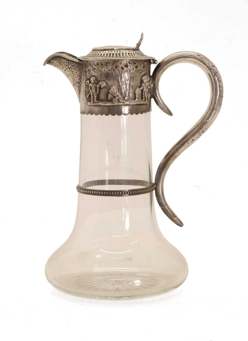 A silver mounted cut glass claret jug,: A silver mounted cut glass claret jug, by John Septimus Beresford, London, 1877, the collar depicting a woodland scene with cherubs, and the spout decorated with ribbons and shell thumb piece 13cm wid