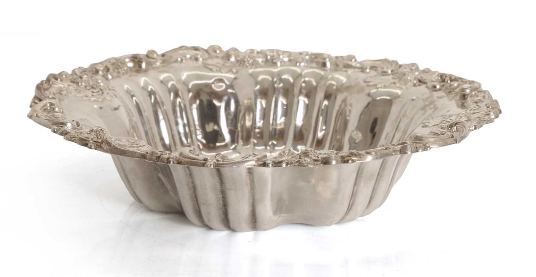 A Sterling silver fruit dish,: A Sterling silver fruit dish, stamped to the base 'STERLING', and marked Bailey, Banks & Biddle Co., with foliate embossed decoration, and monogrammed ot the central field 27cm wide, 6cm high, 12.