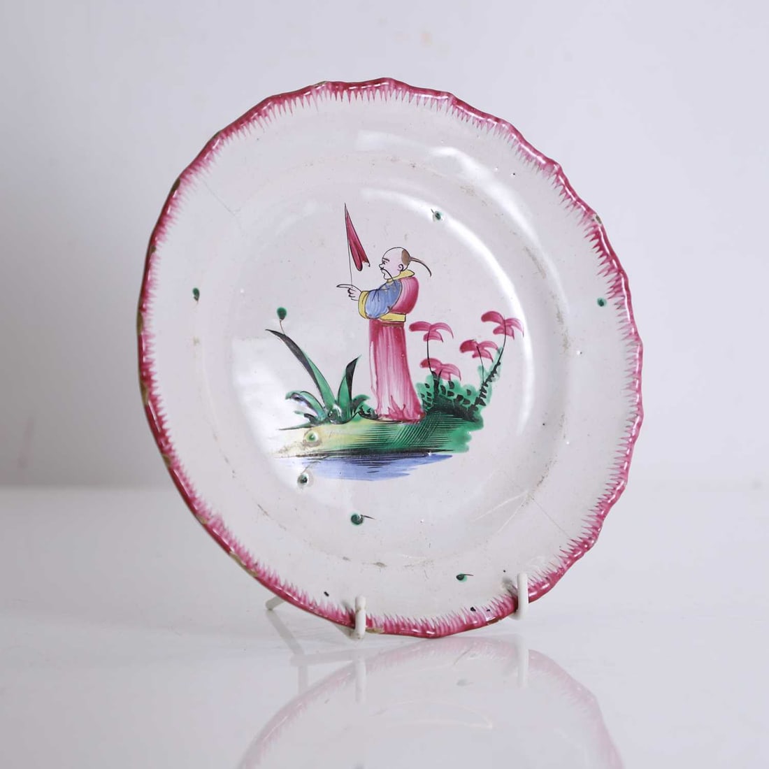 A French Faience plate, 19th century,: A French Faience plate, 19th century, in the Chinese style, with a figure of a man to the centre within a landscape, with a puce border 21.5cm diamter Condition Report: With a pair of hairline cracks.