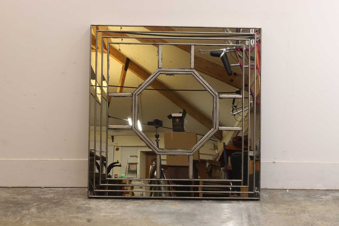 A contemporary wall mirror: A contemporary wall mirror the segmented rectangular plate within a silvered frame 123 x 123cm