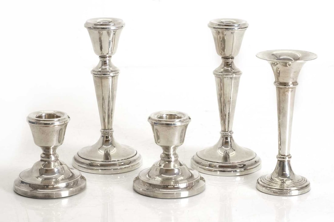 A collection of silver candlesticks,: A collection of silver candlesticks, to include a pair with shaped column, by D Bros, Birmingham, 1973, another smaller pair by A T Cannon Ltd, Birmingham, 1981, and another bud vase, all filled The
