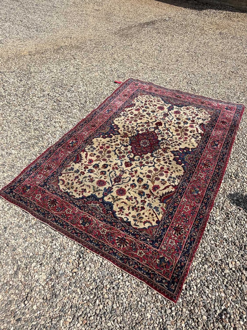 An ivory ground carpet 20th Century, Persian: An ivory ground carpet 20th Century, Persian with scrolling foliate designs, within a banded border 290cm x 193cm Condition Report: wear throughout, frayed to the side cords, marked and discoloured,