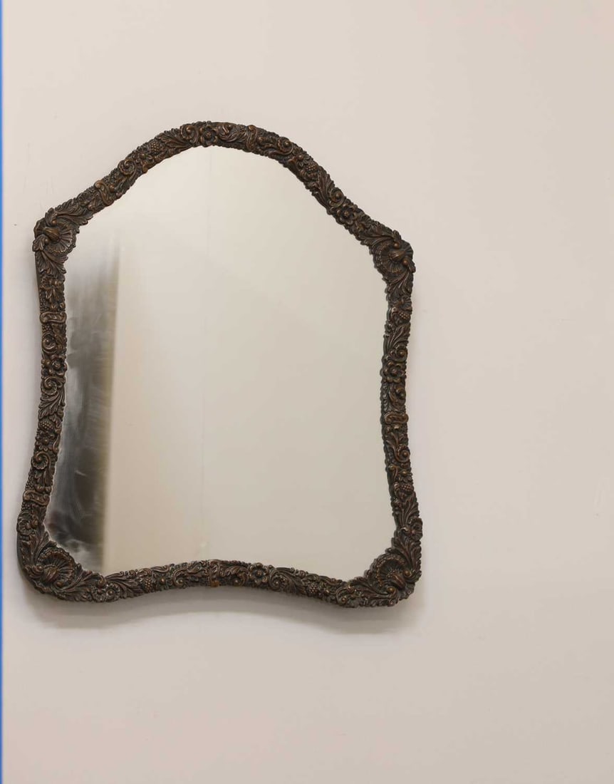 An embossed brass dressing table mirror, early 20th century,: An embossed brass dressing table mirror, early 20th century, decorated with foliate and shell motifs with a shaped plate and ratcheted stand 52 x 44cm