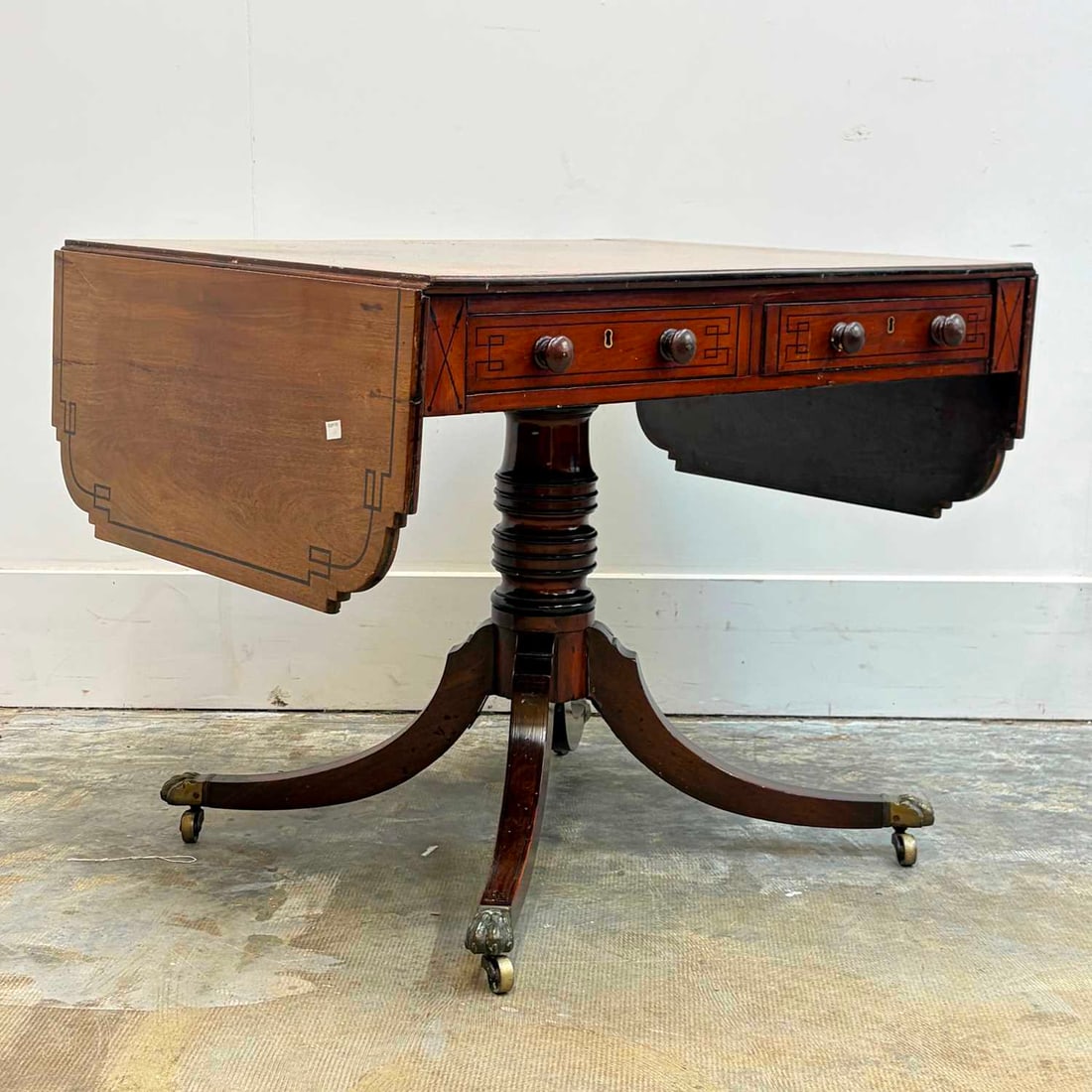 A late Regency mahogany and ebony sofa table, 19th century,: A late Regency mahogany and ebony sofa table, 19th century, the rectangular top with shaped ends above two frieze drawers and opposing dummies, on four outswept legs decending onto paw feet