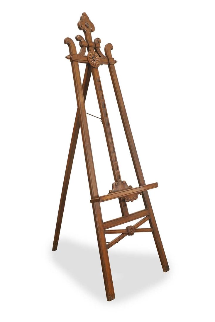 An artists easel, early 20th century,: An artists easel, early 20th century, walnut, with a large carved florette to the centre, and carved detail to the frame 59.8cm wide, 187cm high