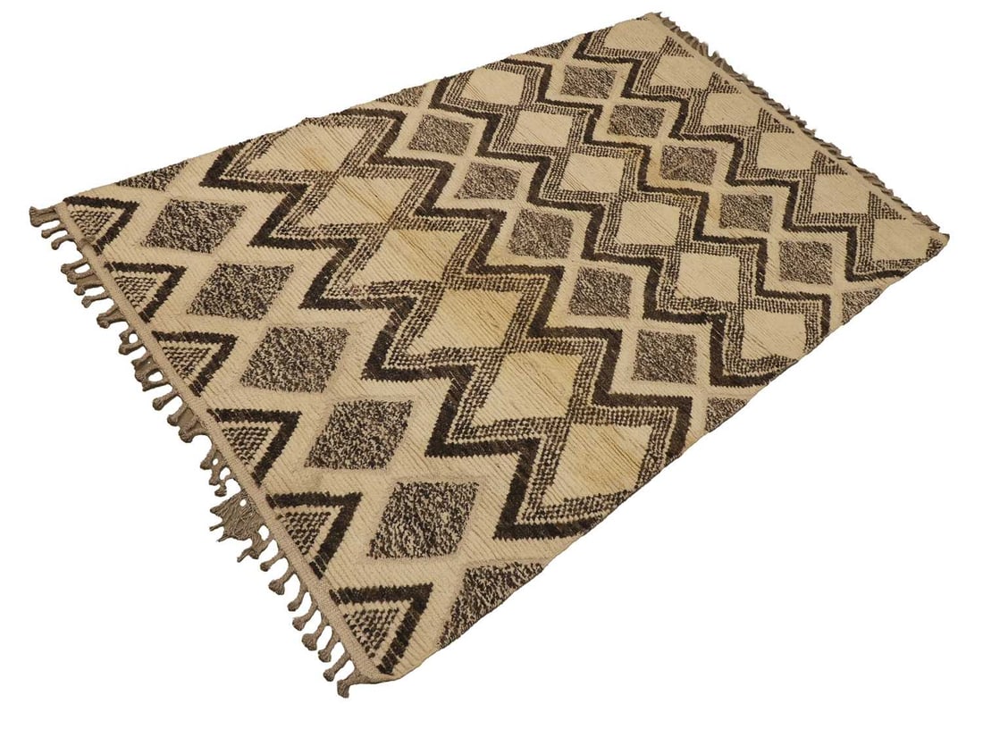 A Berber style wool rug,: A Berber style wool rug, the cream ground woven with an all-over geometric zig-zag and diamond pattern in charcoal and grey tones, with tasselled ends 245 x 153cm Condition Report: With some brownish