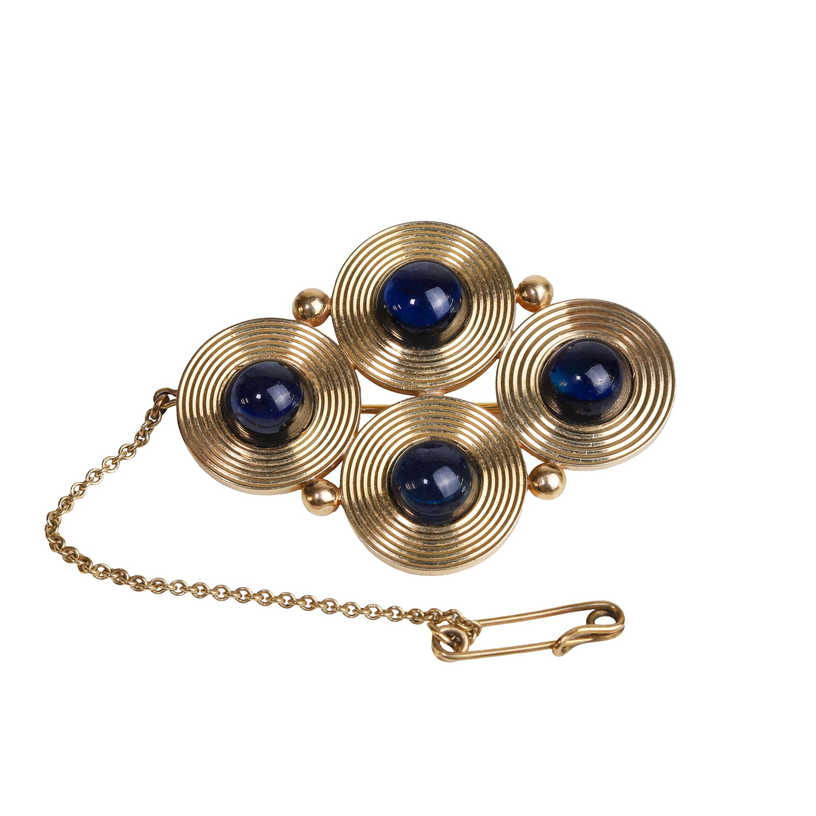 A sapphire brooch,: A sapphire brooch, composed of four incised discs set with round cabochon sapphires to the centre of each and interspaced with gold balls with a pin and roller catch fitting with a safety chain,