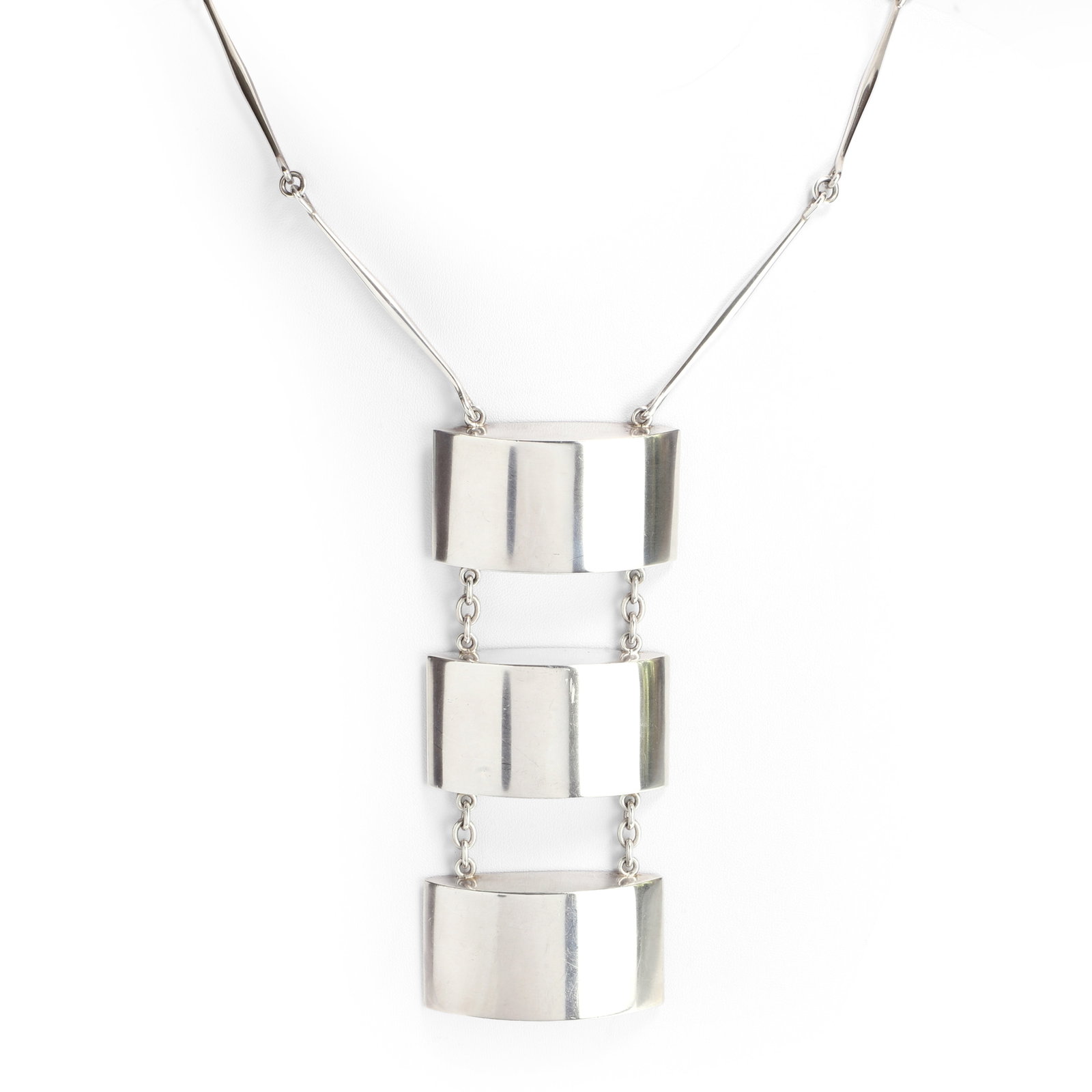 Astrid Fog for Georg Jensen, a modernist silver necklace,: Astrid Fog for Georg Jensen, a modernist silver necklace, model no. 127; with a chain composed of elongated tapered bars hinged with jump rings and a pendant drop of three domed, flat back, oblongs jo