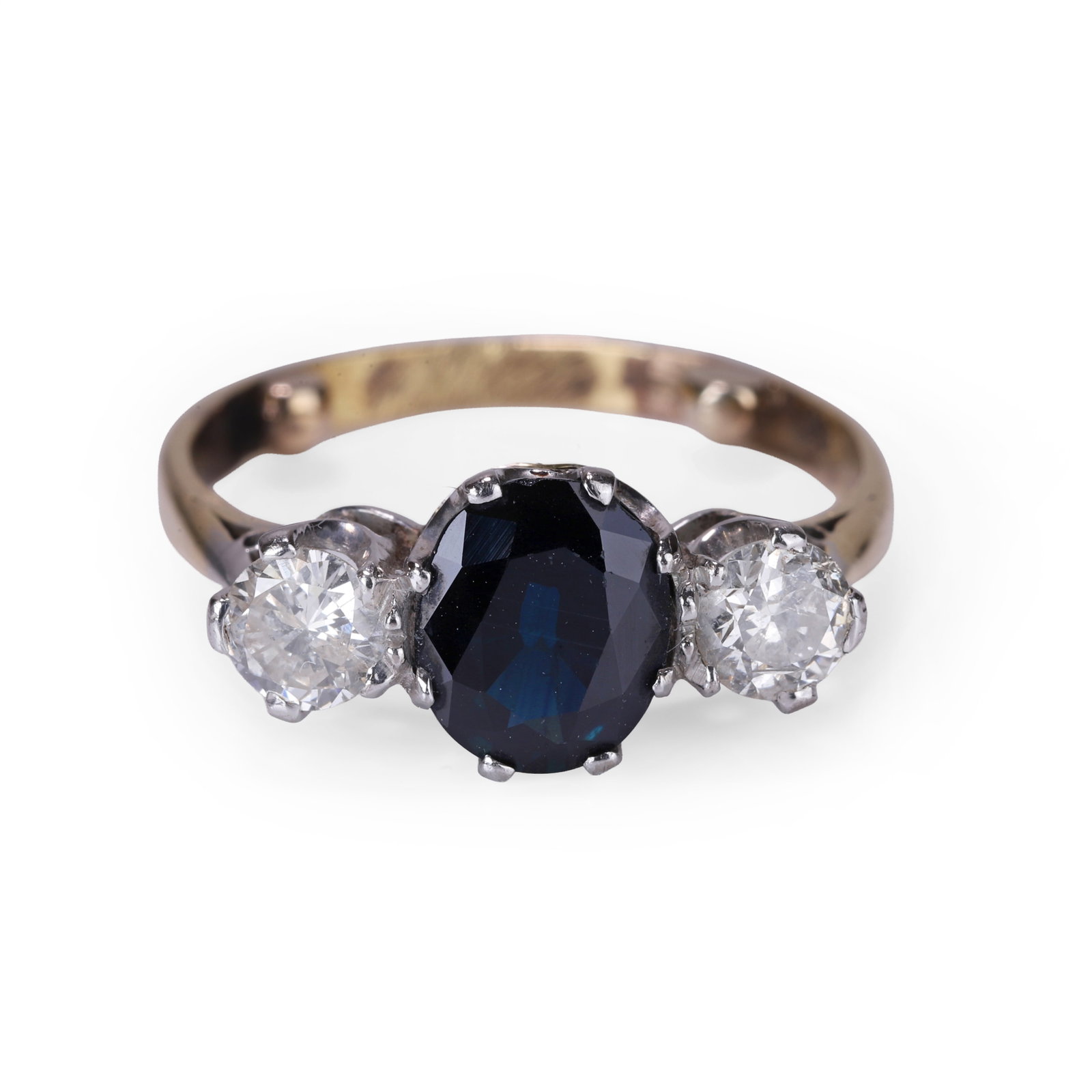 A sapphire and diamond three stone ring,: A sapphire and diamond three stone ring, claw set in white with an oval cut sapphire, flanked to either side by round brilliant cut diamonds, all to a yellow under bezel and tapered chenier shoulders,