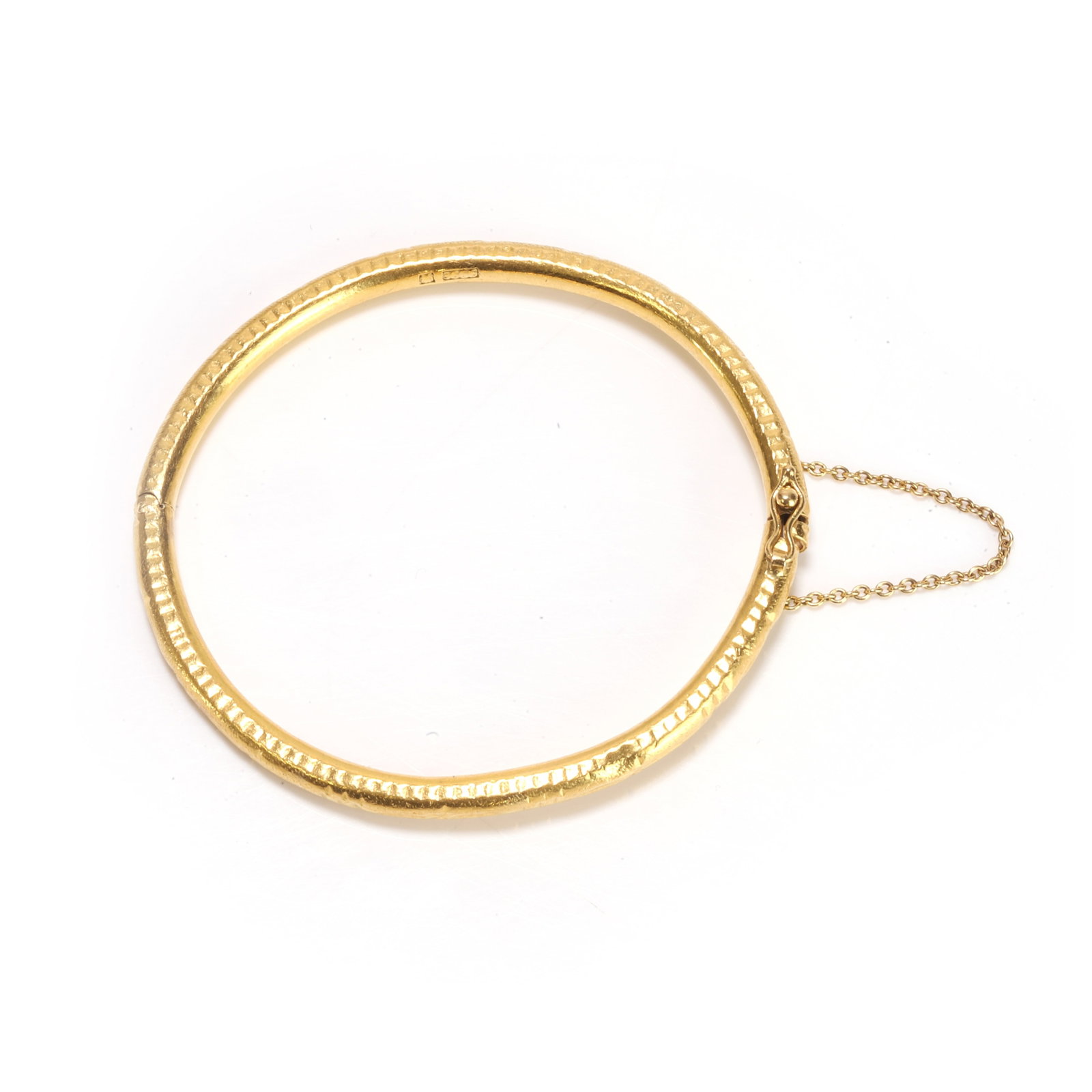 An engraved bangle,: An engraved bangle, with incised band and dart design, integrated clasp with figure of eight catch and safety chain, stamped 900 and tested as approximately 21ct gold (Internal diameter 6.4cm; 29.4g) 