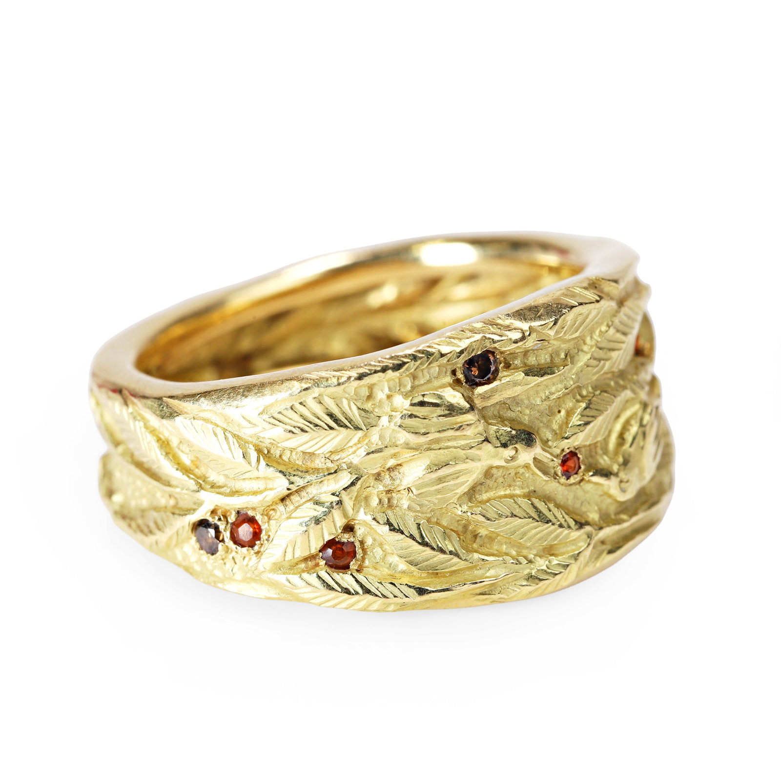 An 18ct gold gemstone set ring, designed by Ortwin Thyssen of Canterbury,: An 18ct gold gemstone set ring, designed by Ortwin Thyssen of Canterbury, the textured band with chased bird and foliage decoration, accented with garnet and brown diamonds, hallmarked London 2014, ma