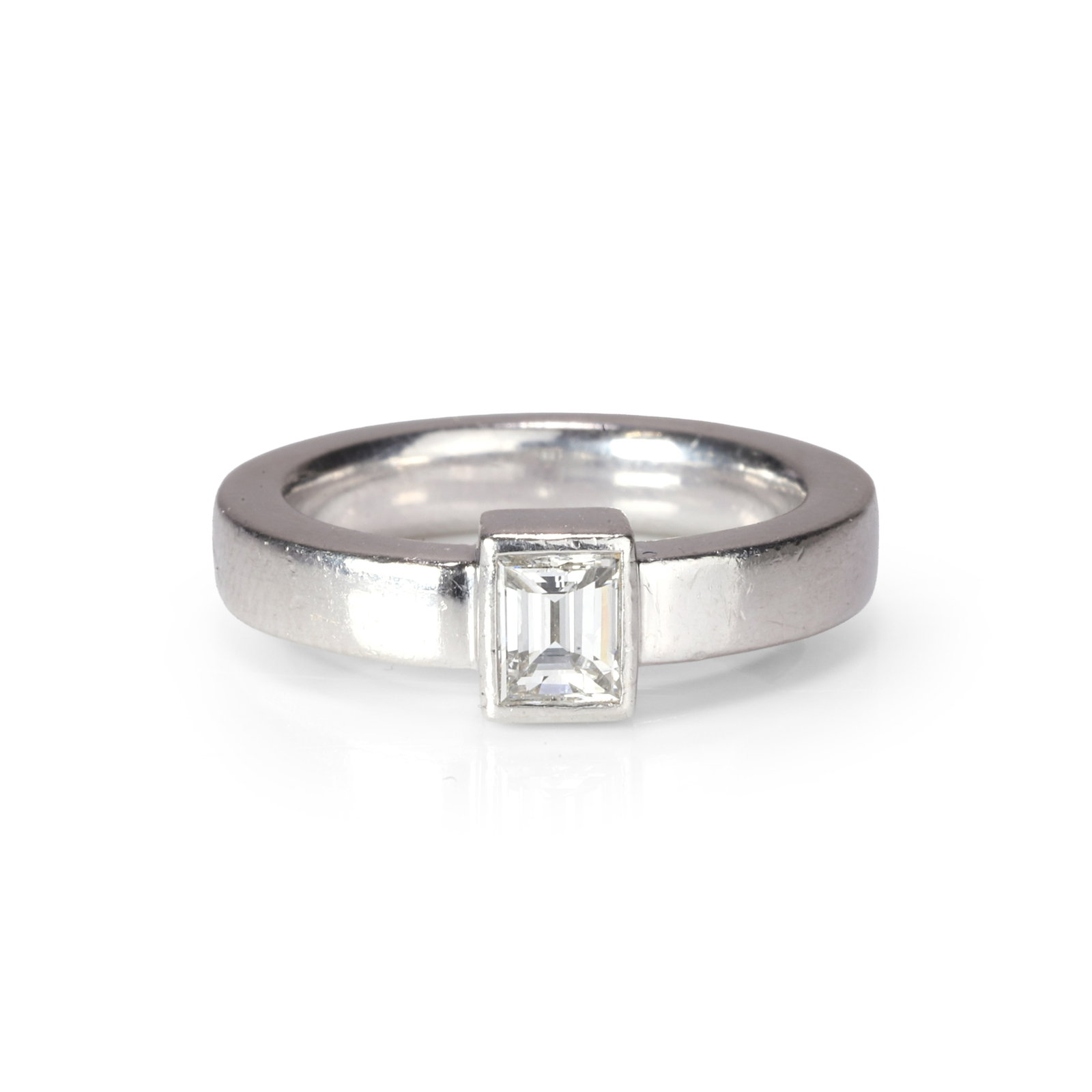 A diamond single stone ring,: A diamond single stone ring, with a rectangular step cut diamond, bezel set to a flat profile band with a comfort fit, stamped pt 900, tested as platinum (Ring size I; 10g) Footnote: Buying this 