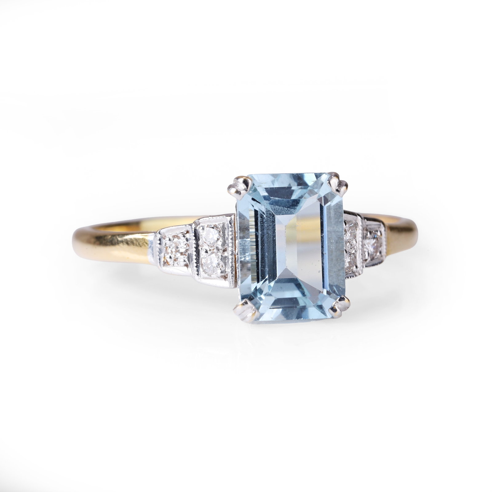 An aquamarine and diamond ring,: An aquamarine and diamond ring, the rectangular step cut aquamarine between stepped shoulders millegrain set with a trio of round brilliant cut diamonds on each side, to a plain yellow metal hoop stam