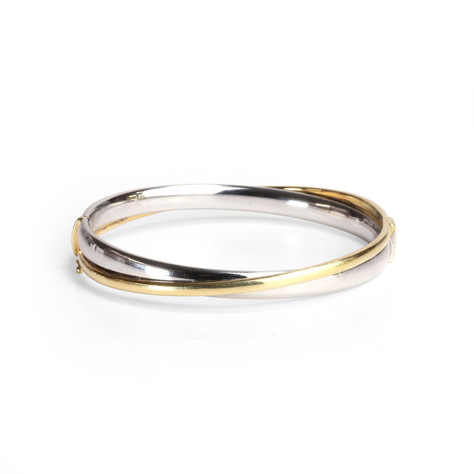 A bi-coloured 18ct gold bangle,: A bi-coloured 18ct gold bangle, of hollow form and oval shape, white gold court profile with yellow gold cross over, knuckle joint hinge and integrated clasp with figure of eight safety clip. Stamped 