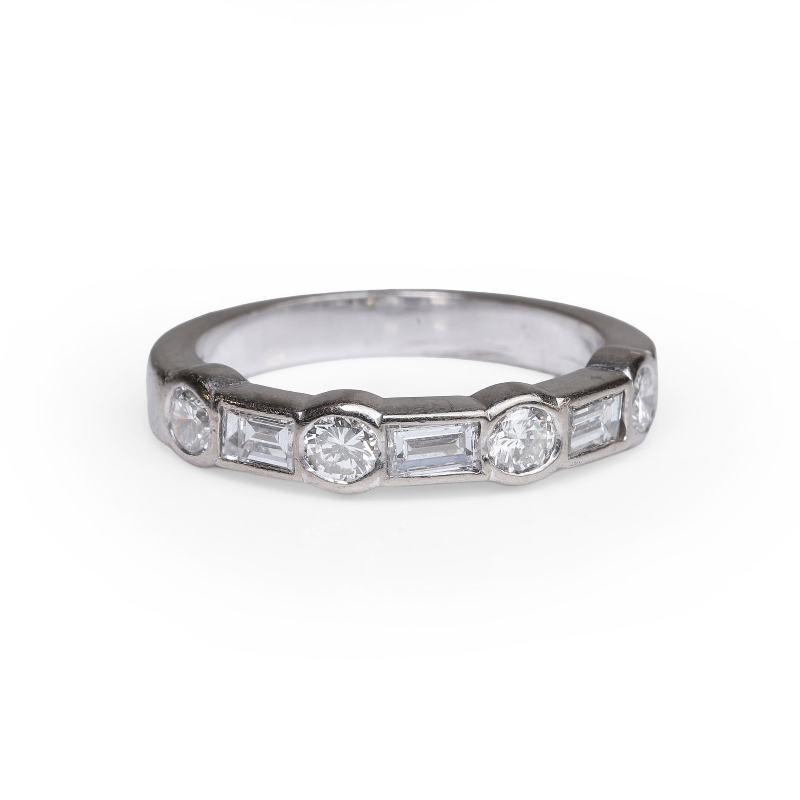 A diamond seven stone half eternity ring,: A diamond seven stone half eternity ring, composed of four alternatively rub over set round brilliant cut diamonds and three baguette cut diamonds. Stamped 18ct and tested as approximately 18ct gold. 