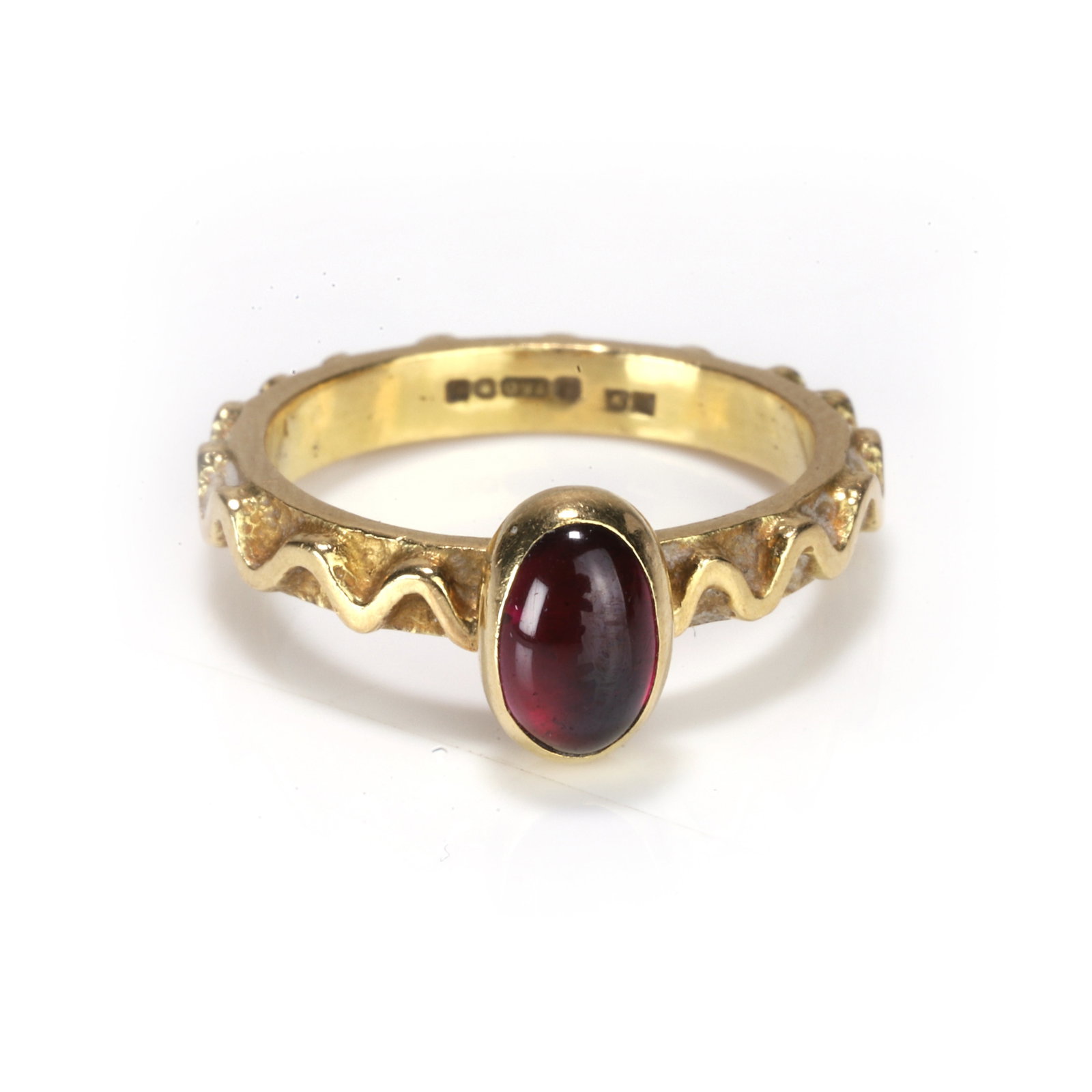 An 18ct gold cabochon garnet ring,: An 18ct gold cabochon garnet ring, centred with an oval cabochon garnet collet set upon a textured mount with a raised wave design motif, sponsor mark AV for Alan Vallis, London 1997 (Ring size H½