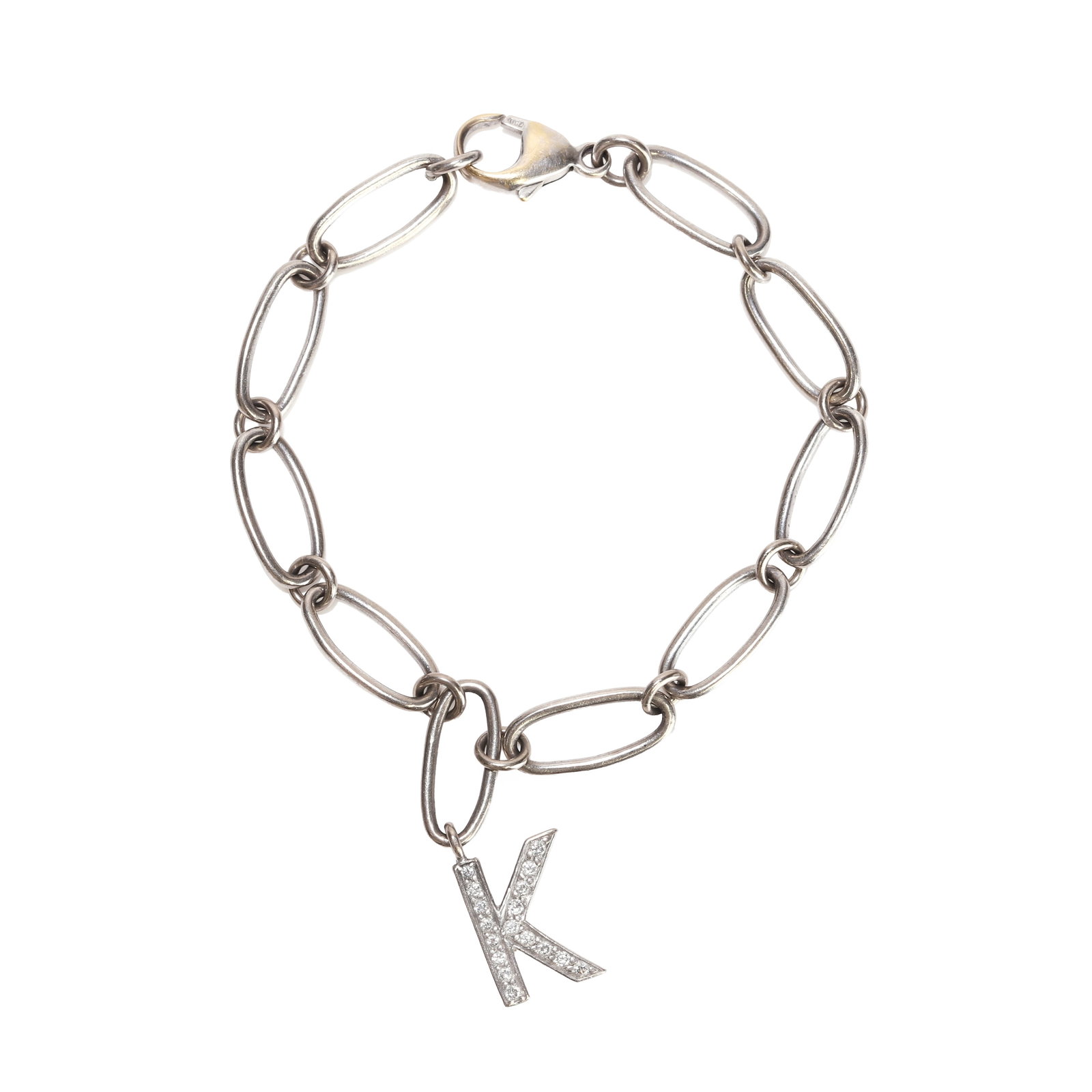A white gold bracelet with a diamond set 'K' charm,: A white gold bracelet with a diamond set 'K' charm, the chain of oval trace form suspending a diamond set 'K' charm, to a trigger clasp stamped 750 (Length 19.5cm; 17g) Condition Report: Scratches and